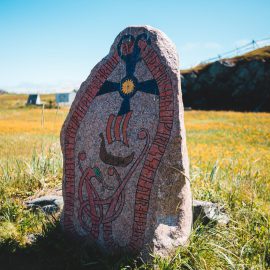aged nordic runestone located on blooming field in countryside