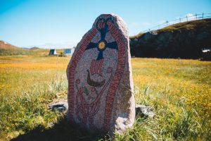aged nordic runestone located on blooming field in countryside